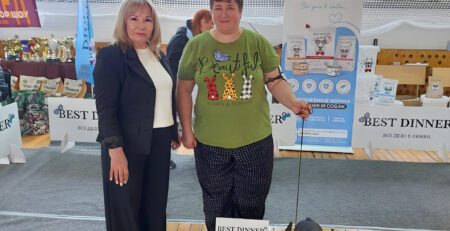 Иштар в стойке на деревянном подиуме ринга, рядом судья и хендлер